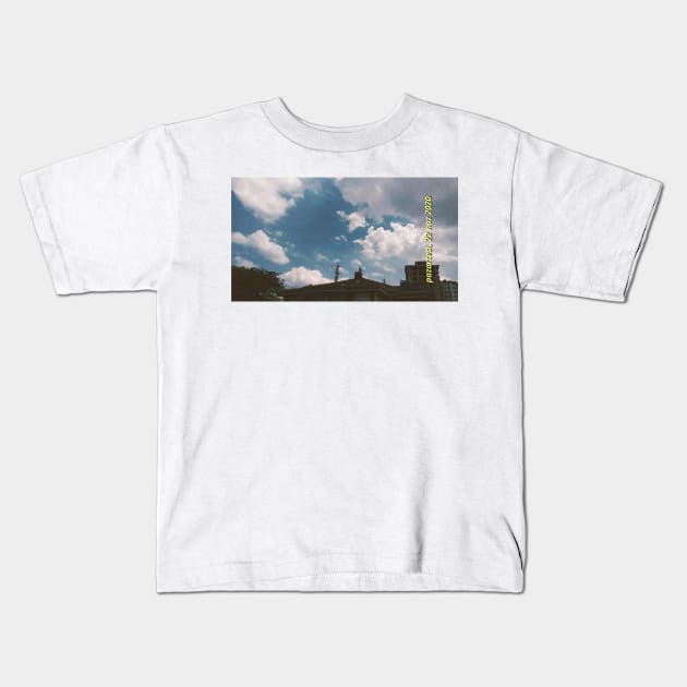 Blue cloudy sky and buildings Kids T-Shirt by ermeteke